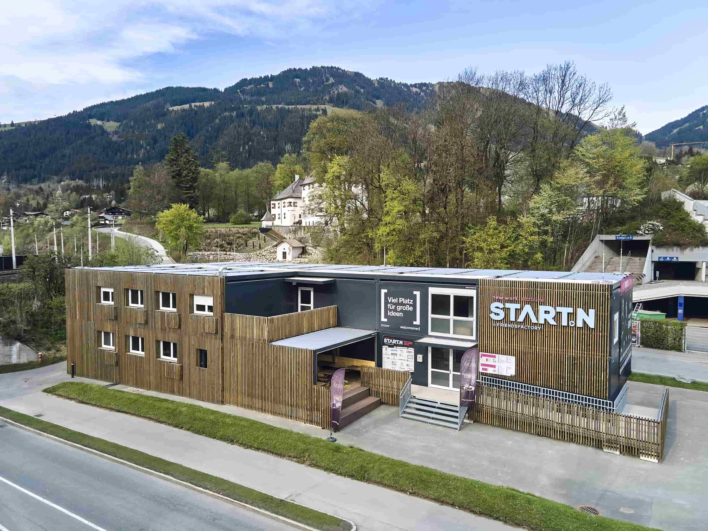 Containeranlage mit Holz Außenverkleidung mit gebirgigem Hintergrund