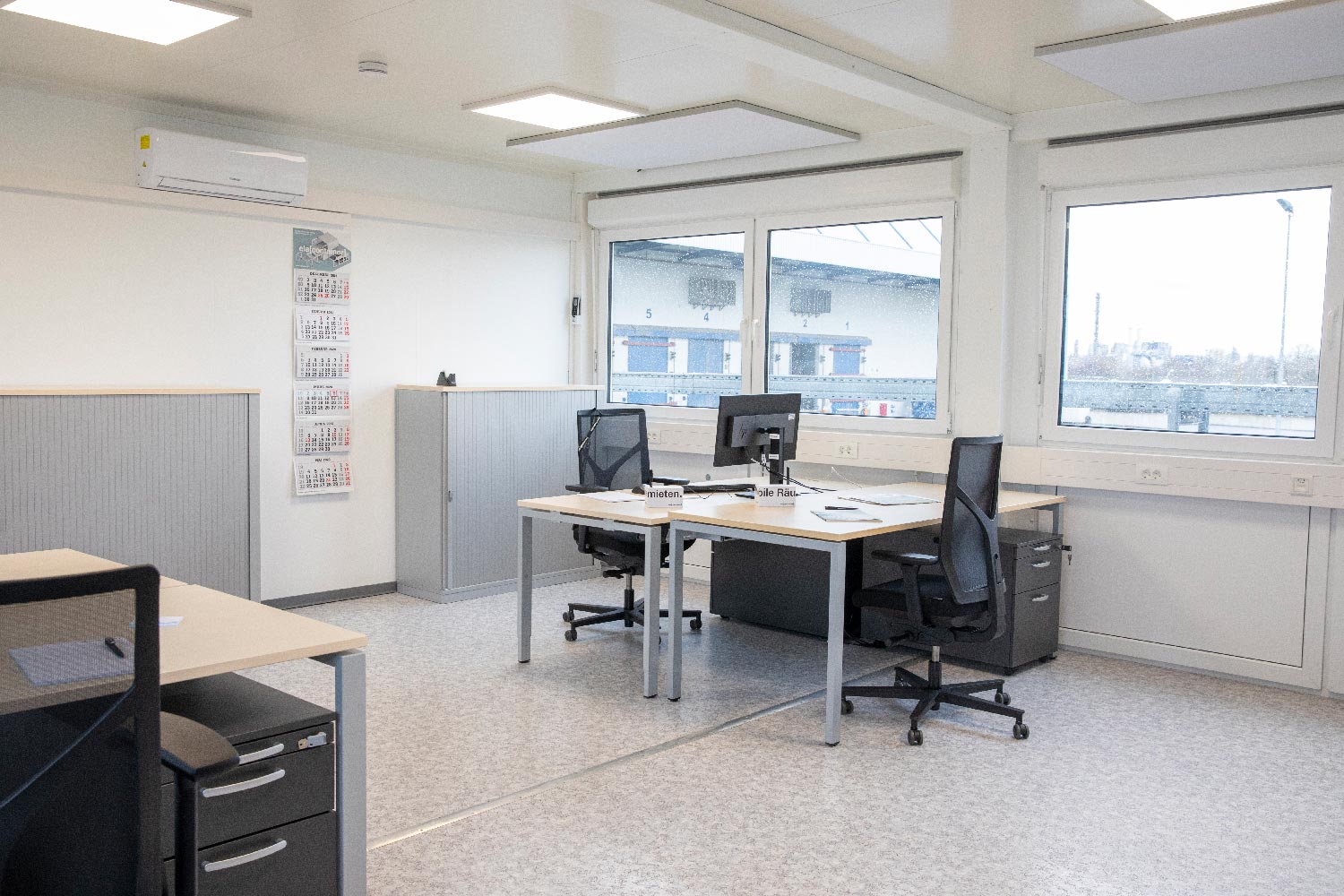 Bürocontainer mit zwei Schreibtischen in der Innenansicht