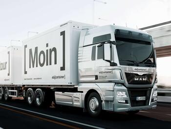 LKW mit Container aufgeladen und Moin-Schriftzug an der Seite
