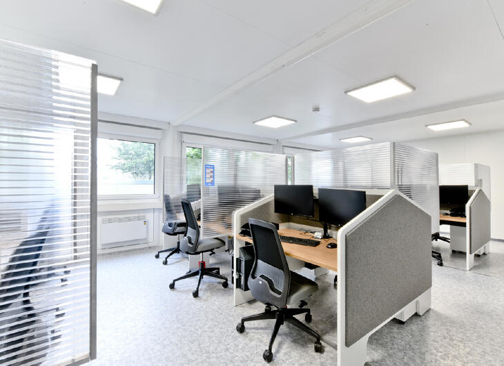 Bürocontainer von innen mit ausgestatteten Tischen und Trennwänden